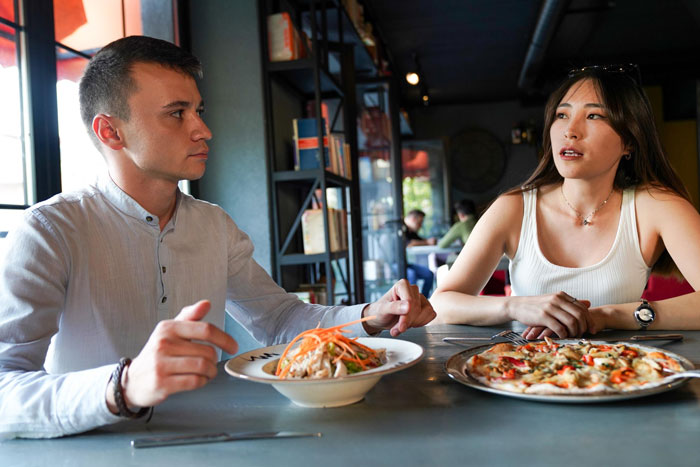 Two people seated at a table in a restaurant, discussing while ordering fried pork intestine dishes. Two people seated at a table in a restaurant, discussing while ordering fried pork intestine dishes.