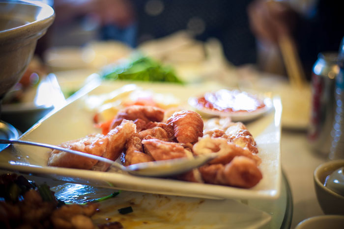 Plate of fried pork intestine served with dipping sauce on a table with chopsticks in a dining setting. Plate of fried pork intestine served with dipping sauce on a table with chopsticks in a dining setting.