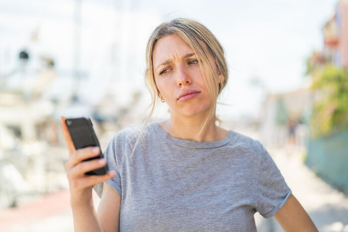 Woman holding her partner's phone with a confused expression.