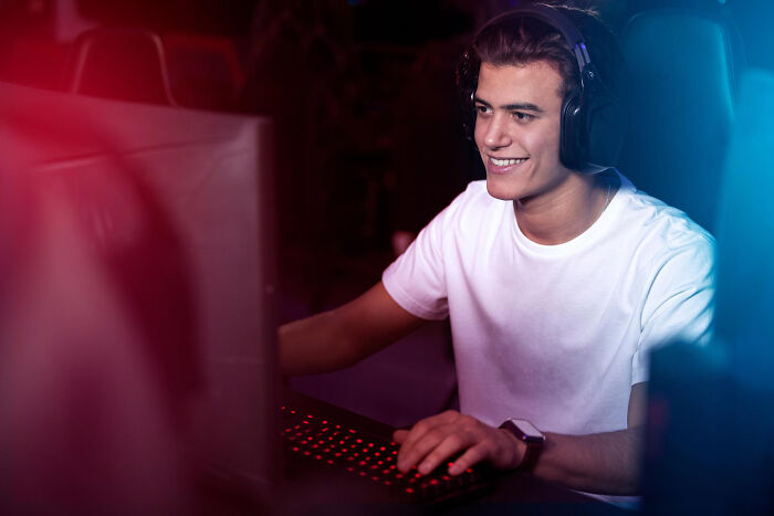 Young man wearing headphones and a white shirt using a computer.
