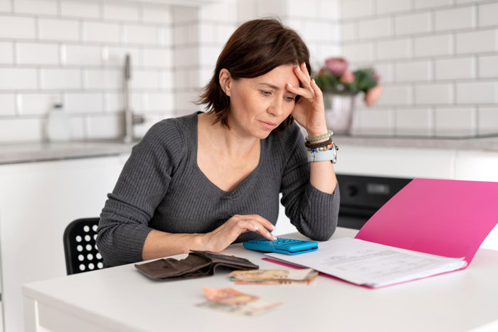 Woman calculating finances with a calculator and documents, stressed about paying off daughter student loans at home. Woman calculating finances with a calculator and documents, stressed about paying off daughter student loans at home.