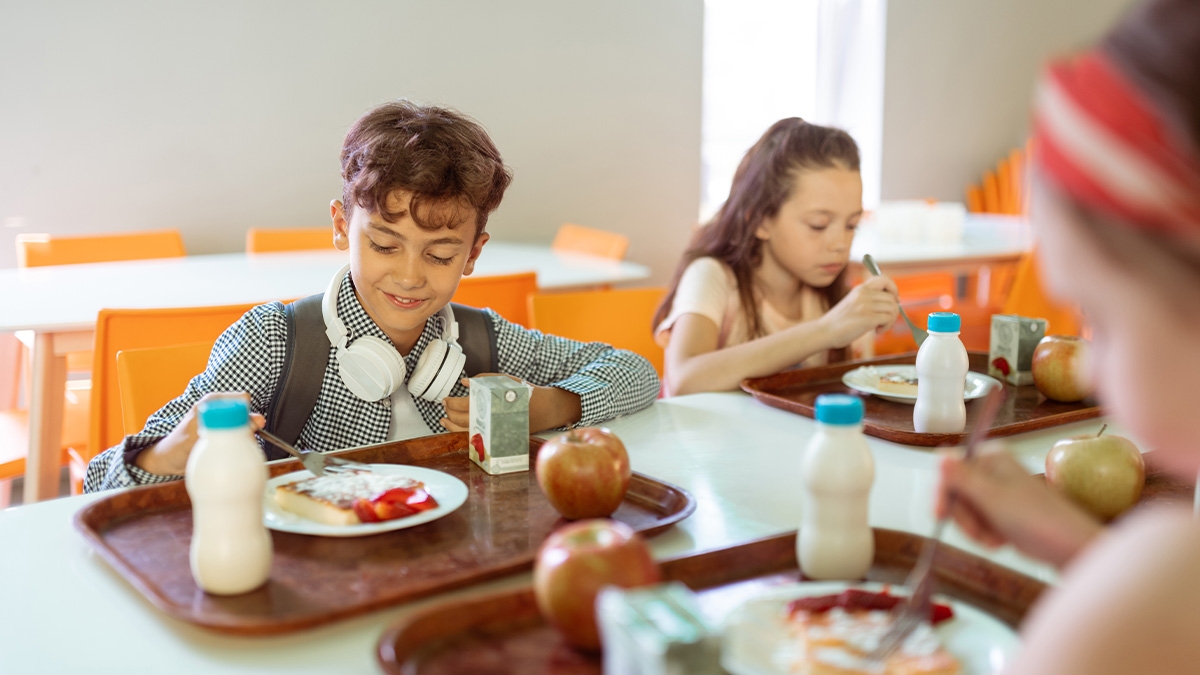 Children enjoying lunch together in a cafeteria, sharing a moment that relates to getting even with a bully.