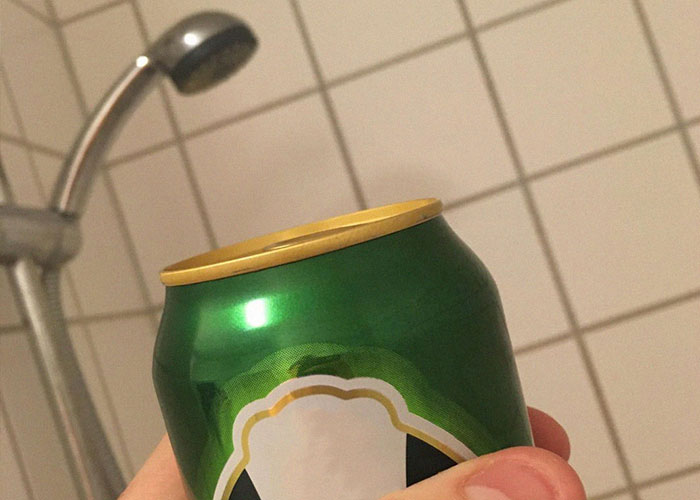 Hand holding a green can near a showerhead, illustrating a life hacks concept that actually work for everyday solutions.