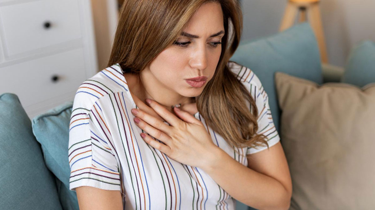 Young woman looking anxious and clutching her chest while sitting alone on a couch at home, feeling creepy and uneasy.