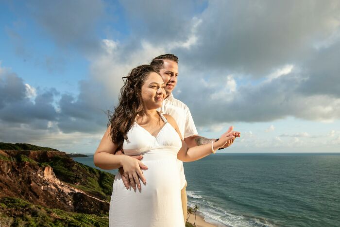 Couple standing on a cliff by the ocean at sunset, symbolizing real-life hexes, odd curses, and spells believed real.