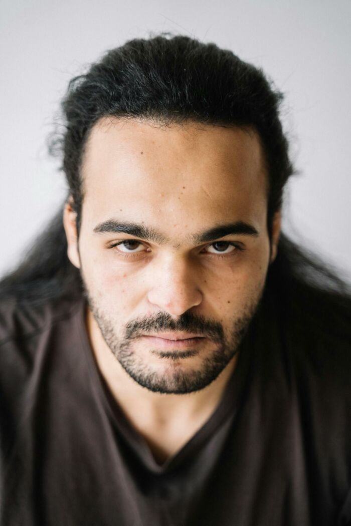 Portrait of a serious man with dark hair and beard, reflecting on challenging tattoo client requests.