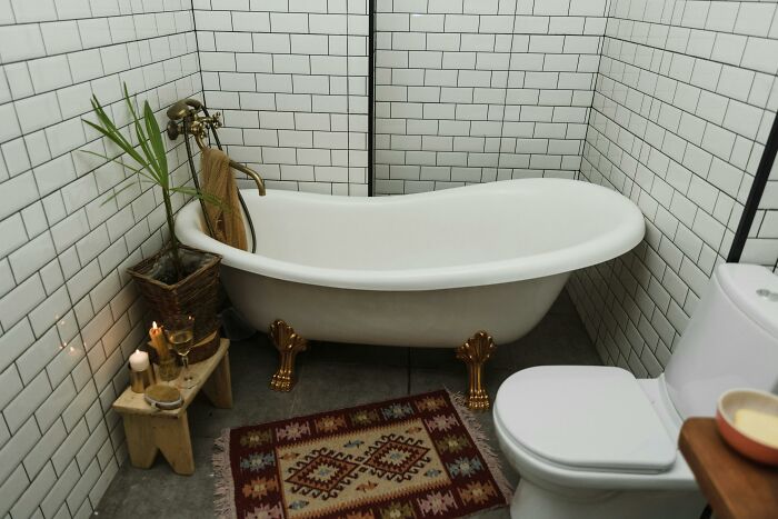 Clawfoot bathtub in a cozy bathroom with white subway tiles, decorative rug, and plants, reflecting nasty exes stories.