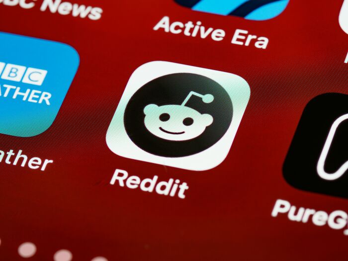 Close-up of a smartphone screen showing the Reddit app icon among overhyped products people say to stop buying.