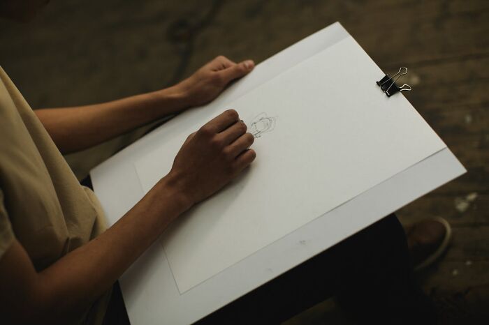 Artist sketching a tattoo design on white paper, highlighting the process of client tattoo requests and artwork creation.