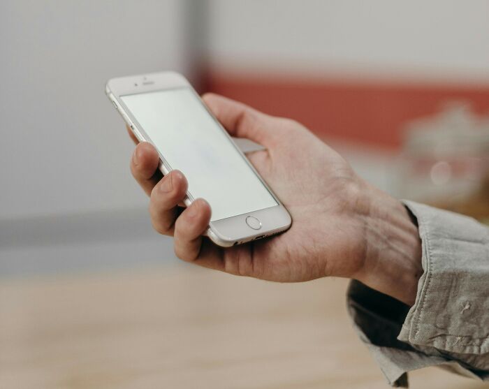 Hand holding a smartphone with blank screen, symbolizing nasty things exes did that shocked and grossed out partners.
