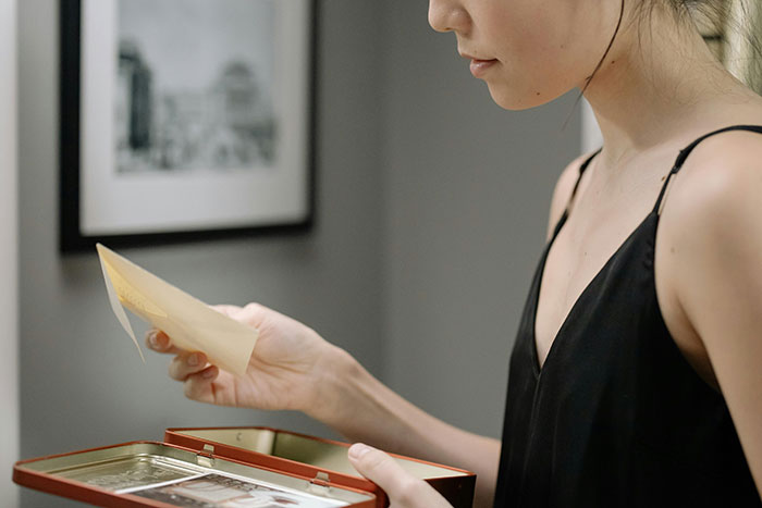 Woman looking at a memory box holding a letter, depicting conflict over ex-GF and late ex-BF keepsakes and hypocrisy.