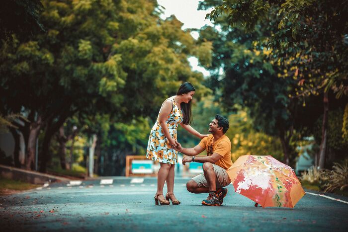Man proposing to woman on a tree-lined street, symbolizing men who married out of pressure sharing life updates.