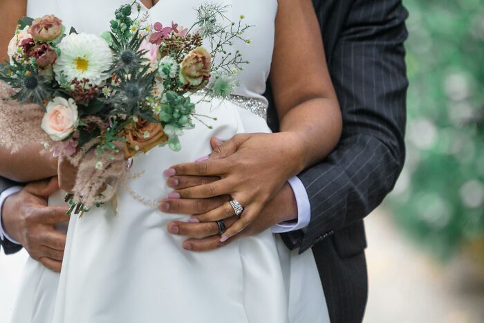 Couple embracing on wedding day with bride holding a bouquet, symbolizing men who married out of pressure life updates.