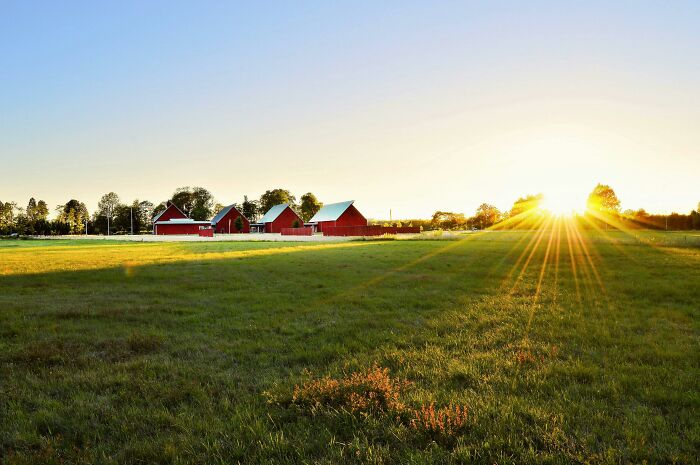 Sunset over rural farm buildings with green fields illustrating a sweet facade hiding manipulation lies or betrayal.