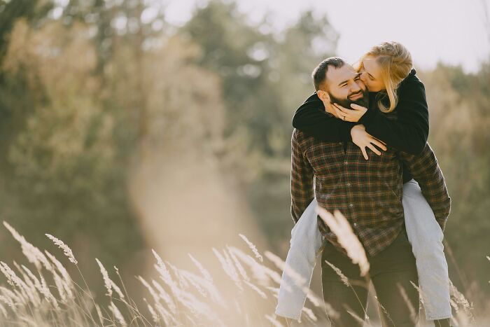 Couple in a field showing a playful moment, illustrating men who married out of pressure sharing their life updates.