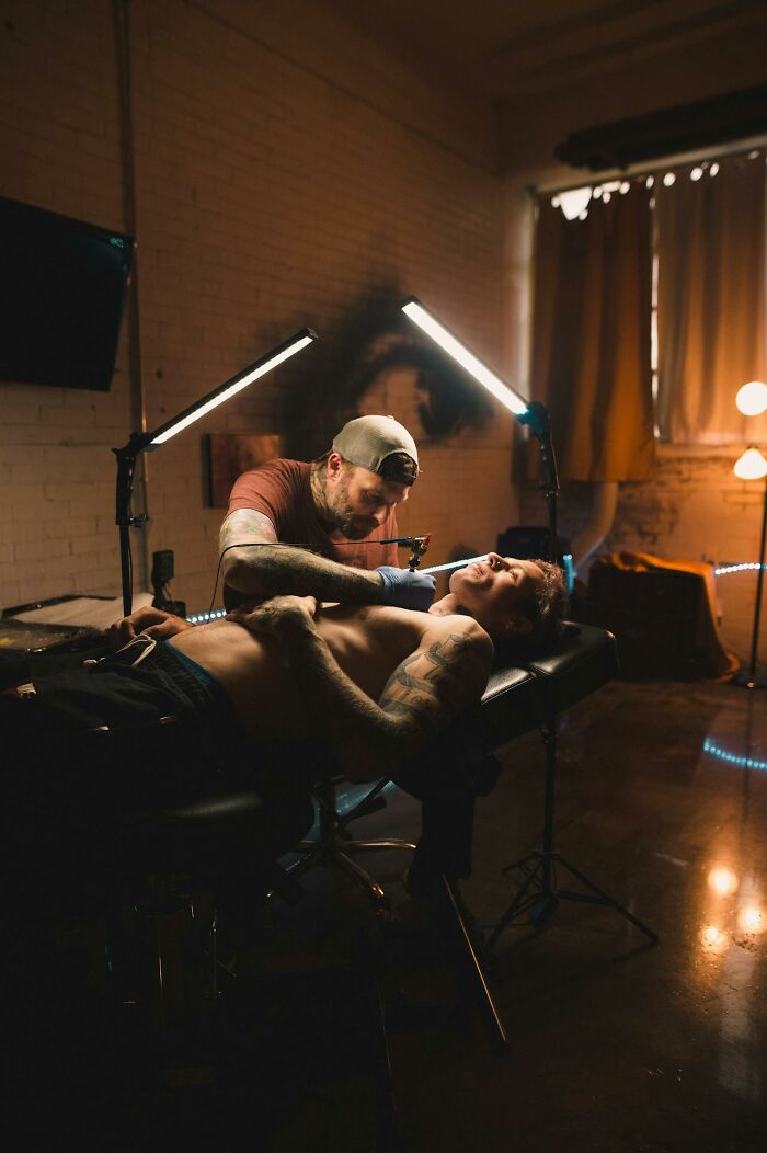 Tattoo artist working on a client’s chest in a dimly lit studio focused on unusual tattoo requests.