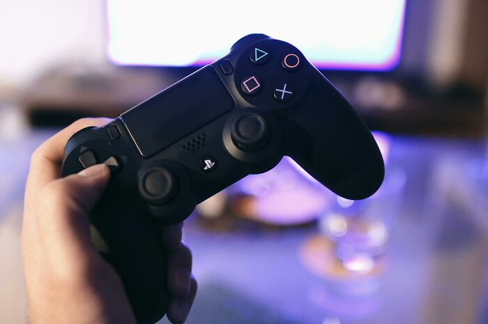 Hand holding a black gaming controller among overhyped products people say everyone should stop buying.