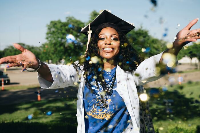 Young woman in a graduation cap celebrating outdoors with confetti, symbolizing things people used to spend hours doing.