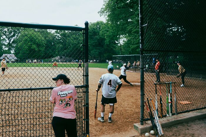 Women watching a mixed softball game, highlighting subtle ways misogyny can creep into daily lives and sports environments.