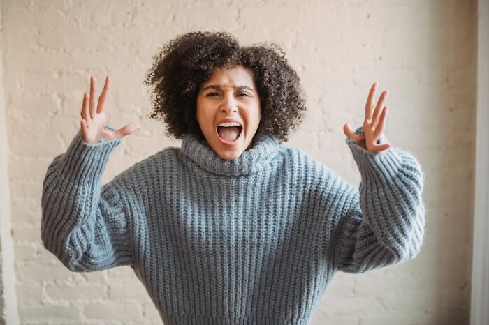 Woman in a gray sweater expressing shock and frustration, illustrating client reactions to worst tattoo requests.