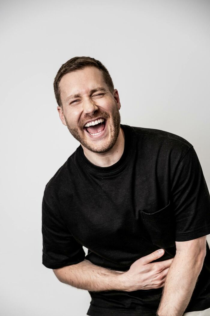 Man in a black shirt laughing heartily, evoking contrast to creepy stories told in the dark woods by a campfire. Man in a black shirt laughing heartily, evoking contrast to creepy stories told in the dark woods by a campfire.