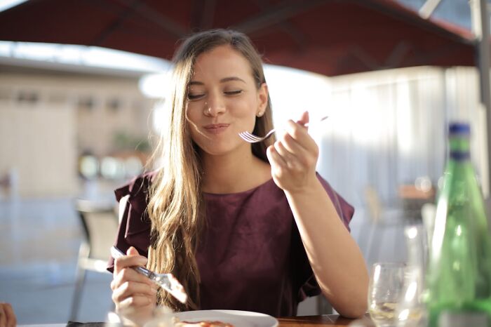 Young woman enjoying a meal outdoors, illustrating social moments related to things women are not allowed to do freely.