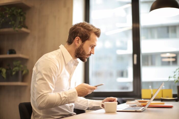 Man working on laptop in modern office, illustrating challenges related to things women are not allowed to do freely compared to men.