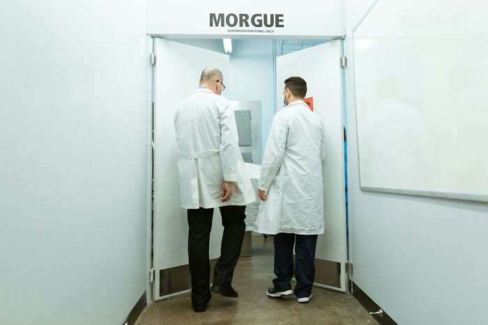 Two medical professionals in white coats entering a morgue, depicting professions not suited as relationship material.