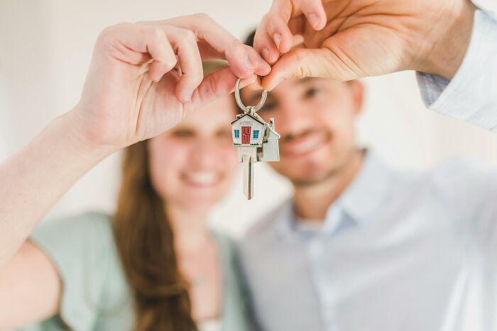 Couple holding a house key with a home-shaped keychain, highlighting subtle ways women notice misogyny daily.