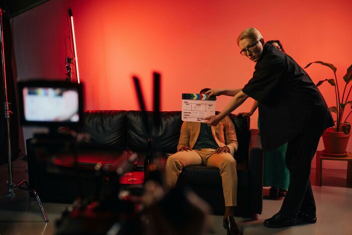 Film crew preparing to shoot a scene on a couch with red background lighting for 2000s movie expert quiz content.