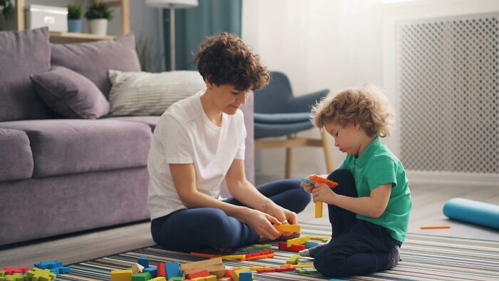 Adult and child playing with colorful building blocks on a rug, illustrating things people used to spend hours doing.