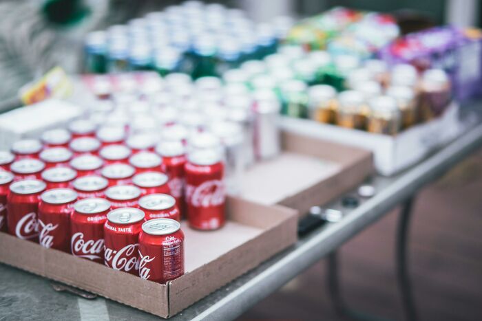Red Coca-Cola cans in cardboard boxes on a table, illustrating overhyped products people say to stop buying.