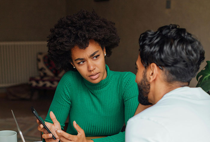 Couple having a serious conversation about memory boxes, highlighting wife wanting man to toss ex-GF's keepsakes.