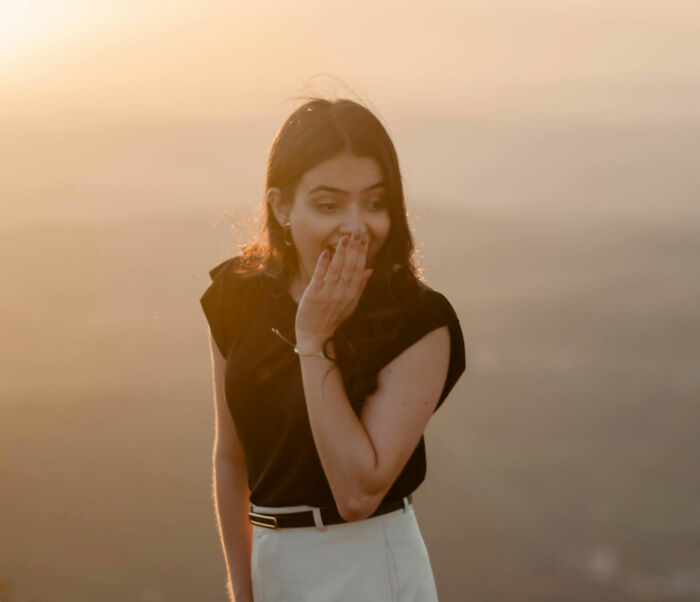 Young woman covering her mouth in surprise during golden hour, illustrating things women are not allowed to do that men can do freely.