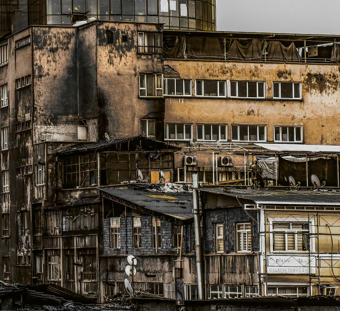 Worn and weathered buildings with numerous windows and satellite dishes hint at the world beneath our feet explored by workers.