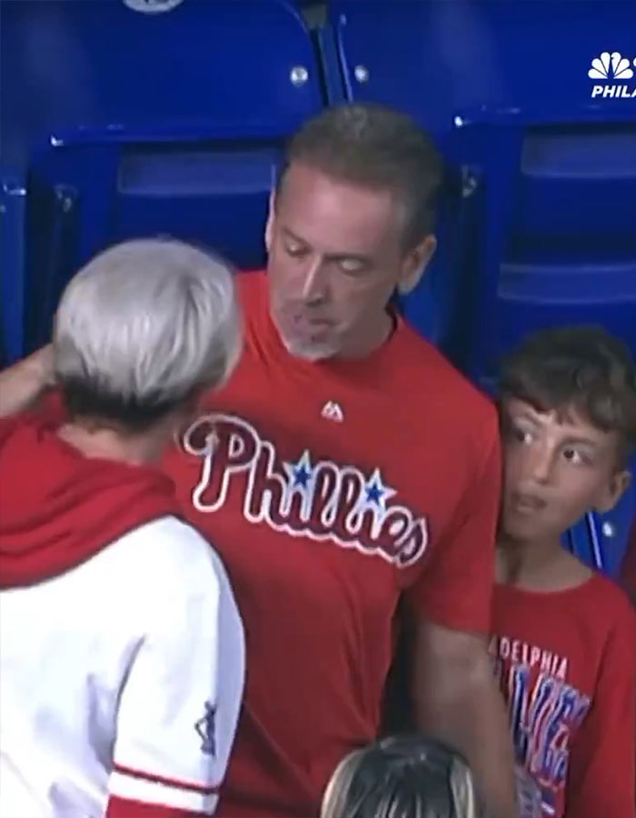 Man in Phillies shirt confronting another person with boy nearby, related to Phillies Karen outrage at home run ball incident. Man in Phillies shirt confronting another person with boy nearby, related to Phillies Karen outrage at home run ball incident.