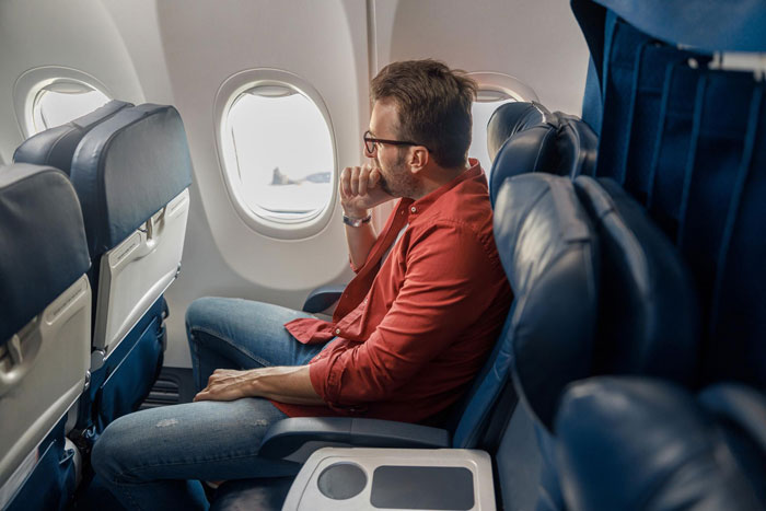 Passenger sitting in airplane seat by the window, looking outside, during a dramatic journey involving a family and seat dispute. Passenger sitting in airplane seat by the window, looking outside, during a dramatic journey involving a family and seat dispute.