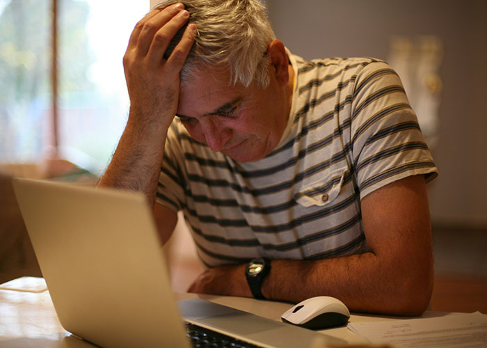 Man frustrated at laptop, illustrating the concept of hilarious job descriptions with a focus on manipulation and product roles.