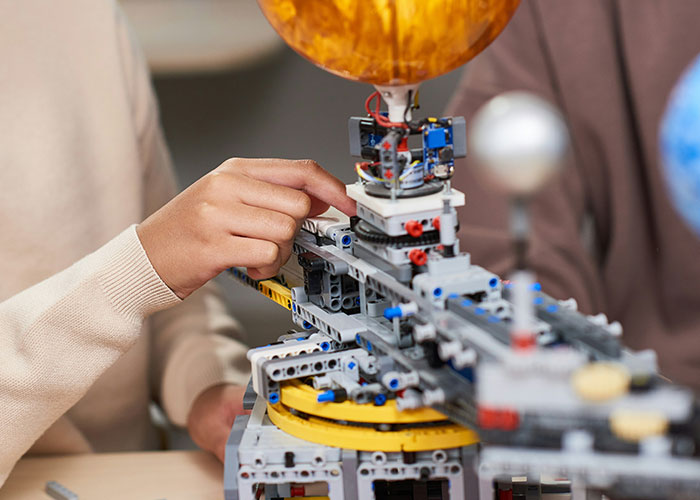 Person manipulating intricate mechanical product with small components and colorful elements on a table.