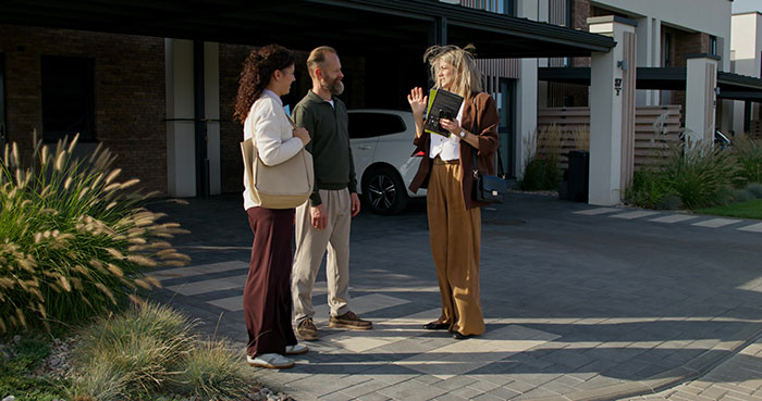 Three adults discussing outside a house, illustrating an HOA dispute over a sibling’s property rights.