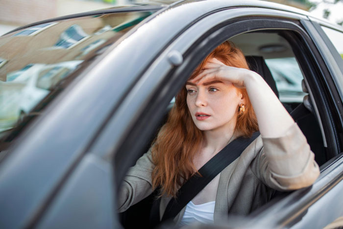 Teen girl driving a car, looking concerned and shielding eyes from sunlight during a school drive preparation. Teen girl driving a car, looking concerned and shielding eyes from sunlight during a school drive preparation.