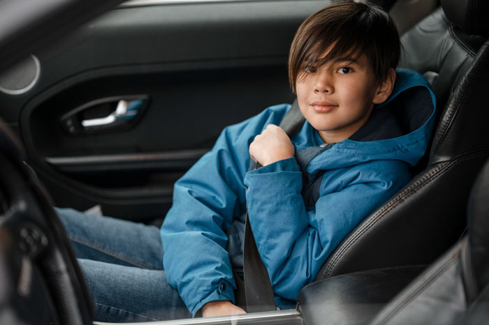 Teen in a blue jacket sitting in car buckling seatbelt, related to hygiene checklist for bro before school drives debate. Teen in a blue jacket sitting in car buckling seatbelt, related to hygiene checklist for bro before school drives debate.