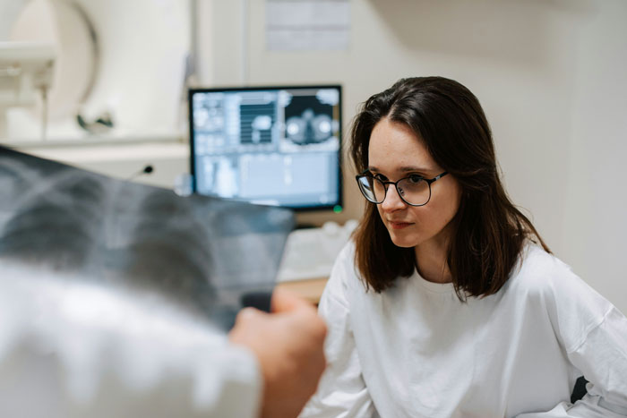 Young woman in glasses attentively listening in a medical setting, reflecting on refusing babysit stepsiblings concerns. Young woman in glasses attentively listening in a medical setting, reflecting on refusing babysit stepsiblings concerns.