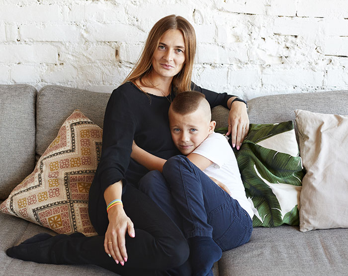 Mom and young boy sitting closely on a couch, illustrating a story about a mom giving her baby up and wanting it back. Mom and young boy sitting closely on a couch, illustrating a story about a mom giving her baby up and wanting it back.