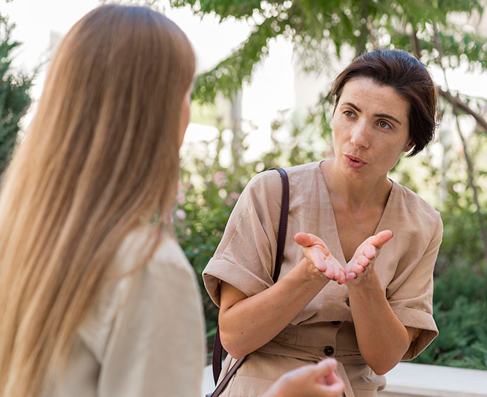 Woman with short dark hair talking seriously to a younger woman outdoors about giving up her baby and wanting it back later. Woman with short dark hair talking seriously to a younger woman outdoors about giving up her baby and wanting it back later.