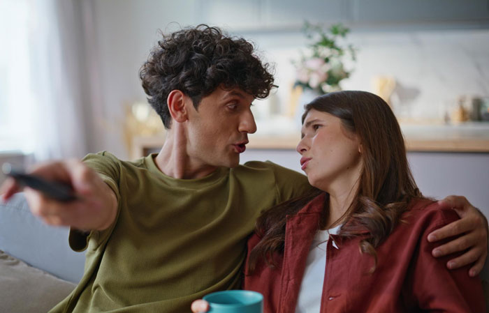 Young man refusing to watch autistic friend's show recommendation while sitting closely on a couch at home. Young man refusing to watch autistic friend's show recommendation while sitting closely on a couch at home.