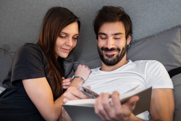 Young man and woman relaxing together while looking at a book, reflecting on refusing to watch autistic friends show recommendations. Young man and woman relaxing together while looking at a book, reflecting on refusing to watch autistic friends show recommendations.