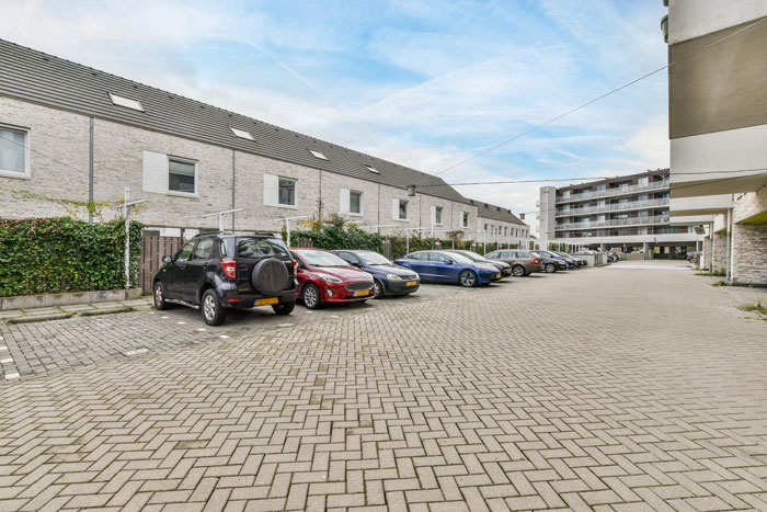 Urban residential parking lot with multiple cars parked along a row, highlighting issues of parking spot disputes and towing. Urban residential parking lot with multiple cars parked along a row, highlighting issues of parking spot disputes and towing.