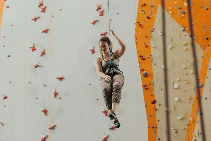 Woman suspended on climbing rope at indoor gym, reflecting on guy considering her his girlfriend after one date Woman suspended on climbing rope at indoor gym, reflecting on guy considering her his girlfriend after one date