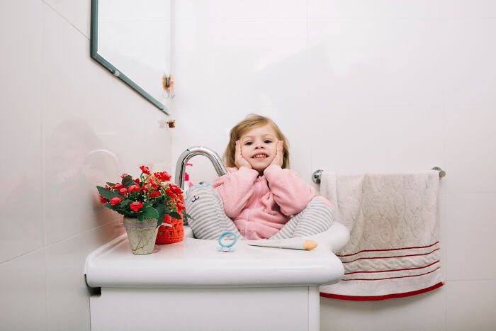 Young child sitting on a bathroom sink wearing pajamas, relating to babysitters' bedtime stories and horror experiences.